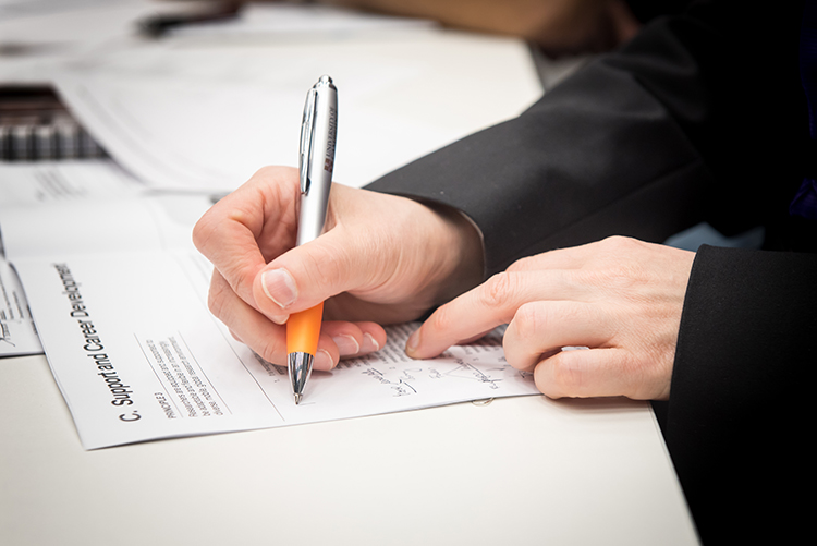 A man's hands holding a pen as he takes notes on the Concordat to Support the Career Development of Researchers