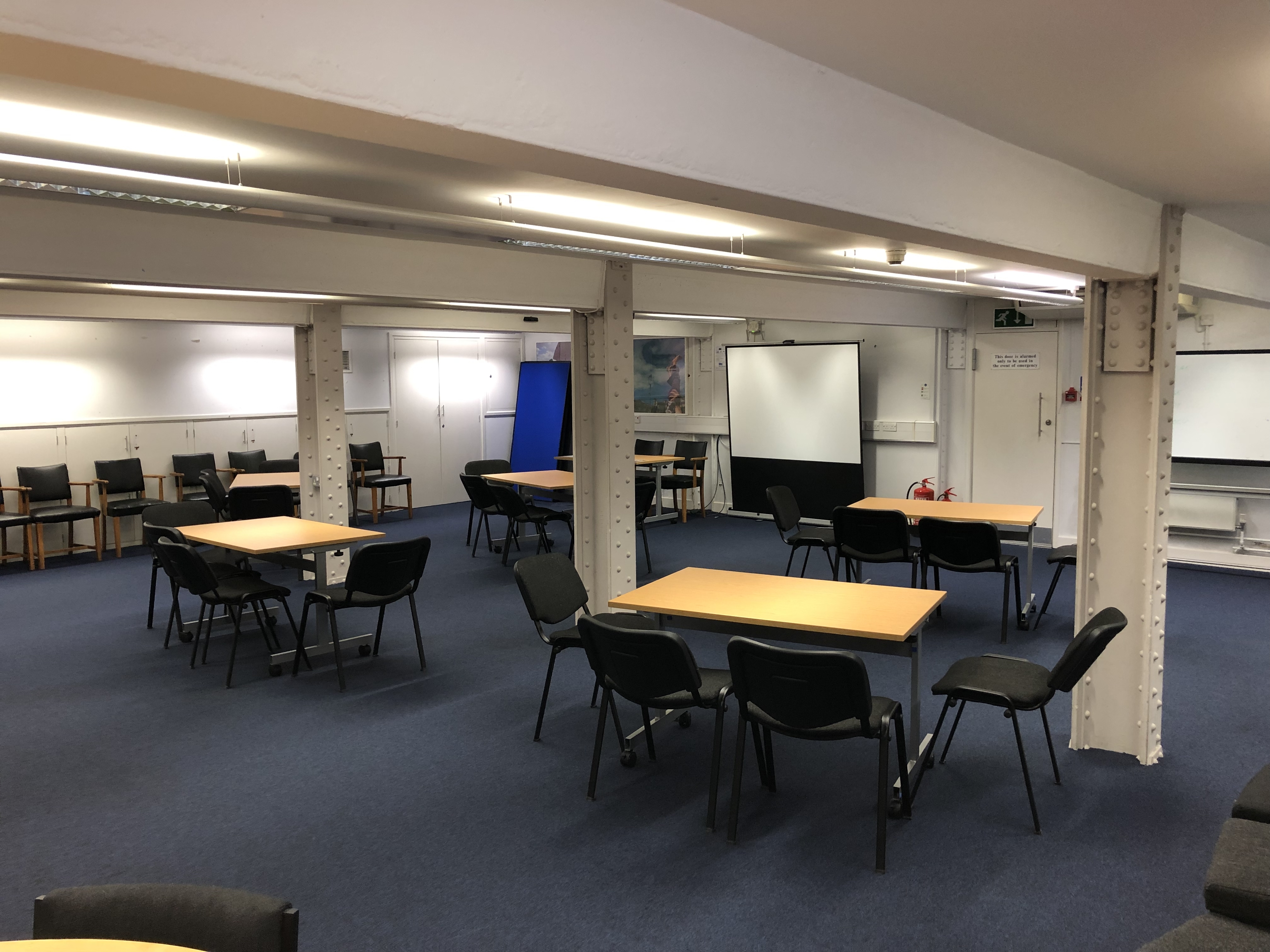 Photograph showing the workshop-style layout of the Eastwood Room - a room with five tables each with four chairs around them.