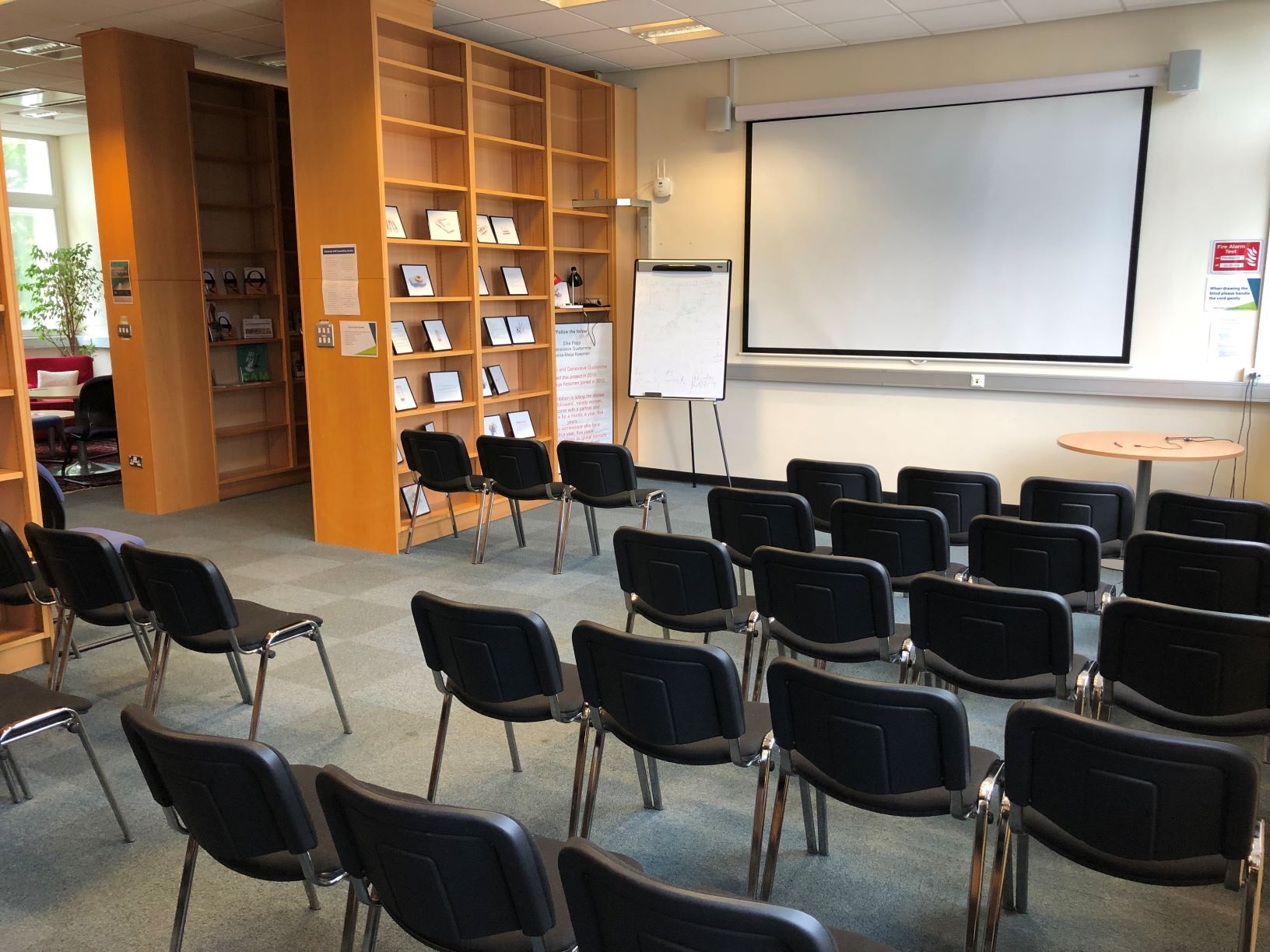 Photograph showing the lecture-style layout of the Newman Library - a room with five rows of chairs facing a projector screen on the end wall.