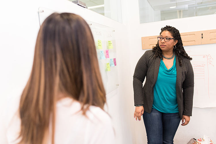 Two women discussing post-its on a whiteboard