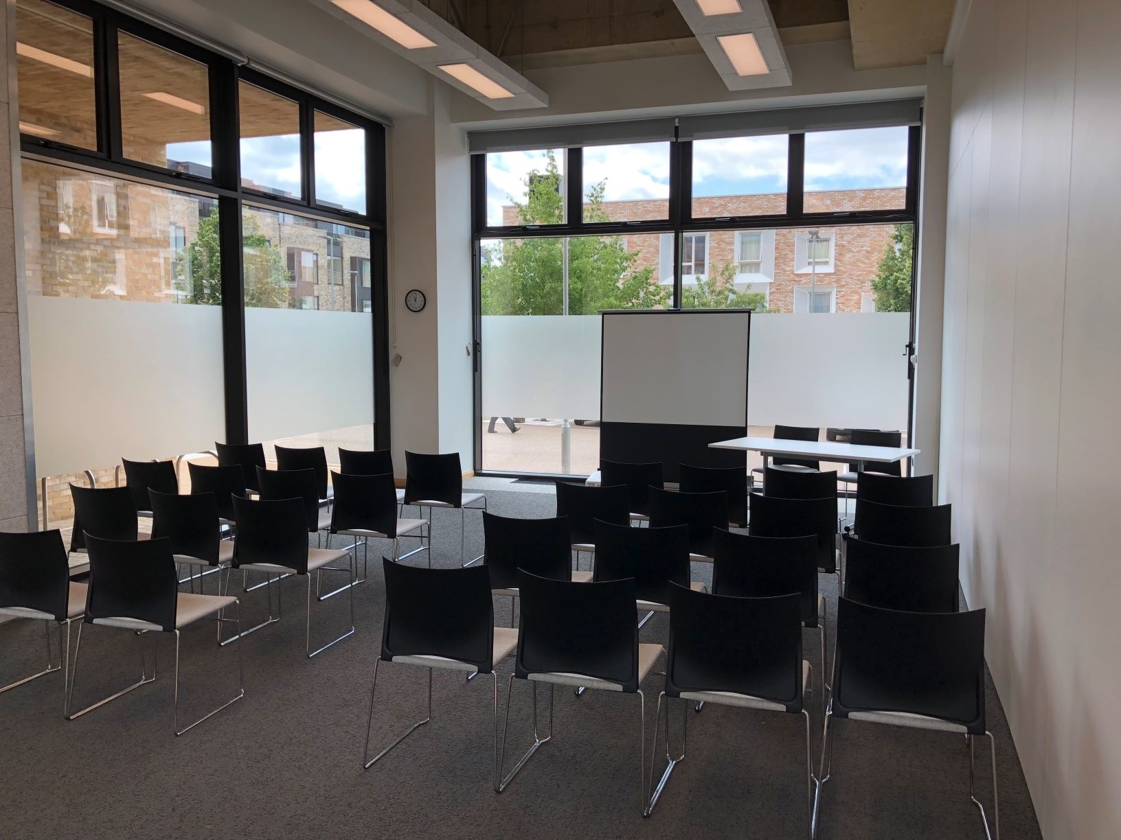 Multi-Function Space lecture layout Photograph showing the lecture-style layout of the Multi-Function Space - a room with four rows of chairs facing a projector screen on the end wall.
