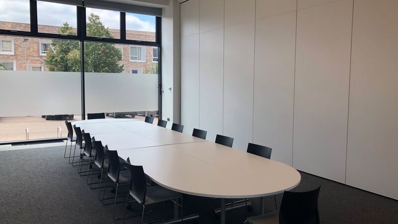 Photograph showing the boardroom-style layout of the Multi-Function Space - a room with fourteen chairs around a large boardroom table.