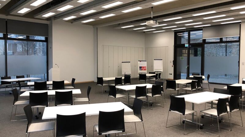 Photograph showing the workshop-style layout of Sanders Hall - a room with twelve tables each with four chairs around them.