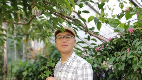Longzhu stands in one of the greenhouses in the Cambridge Botanic Gardens