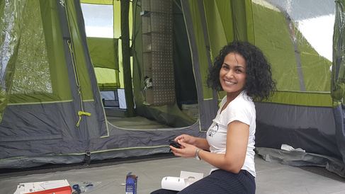 Dilrini sits in a tent entranceway, examining camping equipment